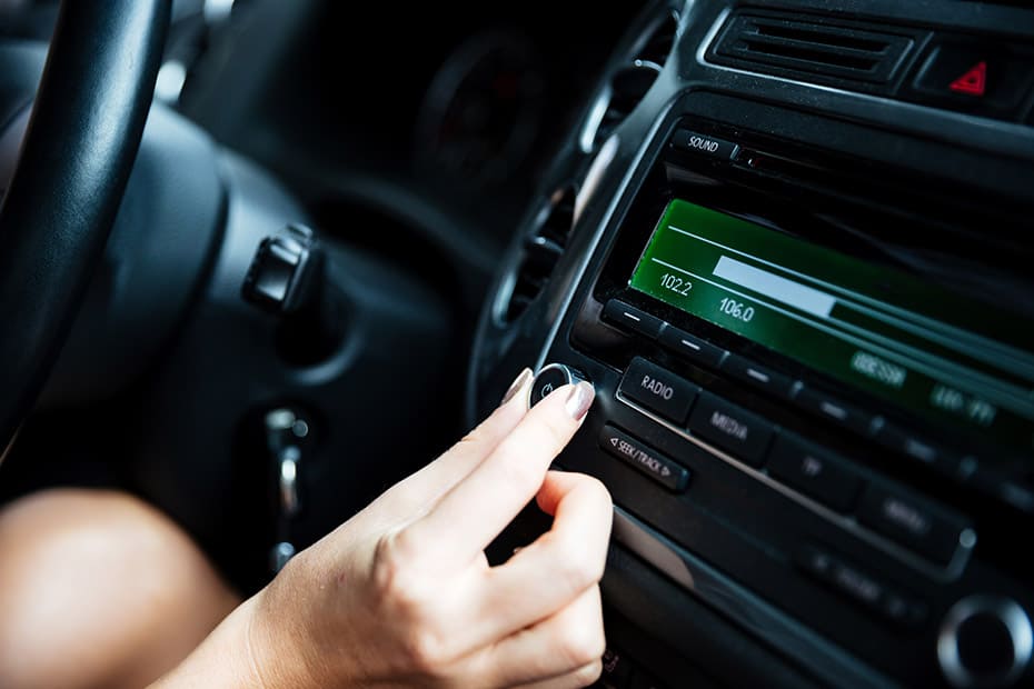 Mujer mano girando el botón de la radio en el coche